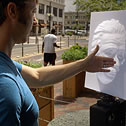 Man holding up his hand in front of a painting of a human face