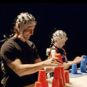 A man and a boy in head-gear with electrodes building towers with plastic cup
